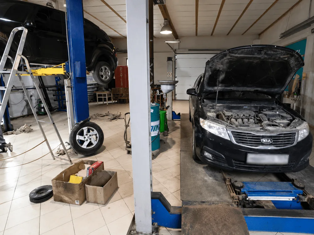 Два подъёмника в боксе автосервиса: один автомобиль поднят, второй — на стенде сход-развала